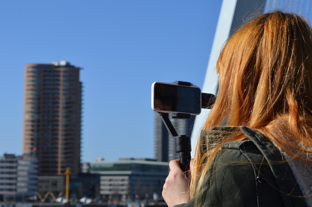 Woman using gimbal and iPhone for video camera.